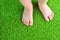 Artificial turf background. Tender foots of a baby on a green artificial grass floor.