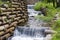 Artificial waterfalls on mountain stream with wooden logs crib wall