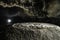 Artificially highlighted limestone formations in a cave with a speleologist in the background