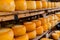 Artisan cheese wheels wooden shelves dairy factory. Food quality, cheesemaking craft