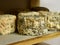 Artisan cheeses in the process of maturation on wooden shelves.