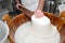 Artisanal preparation of Italian buffalo mozzarella. The cheesemaker collects the mozzarella mass after the curd in the wooden vat