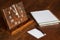 Artisanal wooden clock on the table, with paper to notations