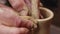 Artisans hands give the spinning clay on the potters wheel shape by sliding his fingers over it, closeup. Potter works
