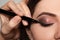 Artist applying black eyeliner onto woman`s face