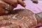 Artist applying henna tattoo on women hand.Close up shot of traditional Indian decorative art mehandi