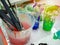 Artist paint brushes in white bucket of water, acrylic colour in plastic cups