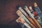 Artist paintbrushes, paint tubes closeup on brown canvas background.