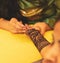 An artist performing mehandi or henna design on female hand