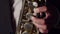 Artist plays the saxophone with hands in close-up. A male saxophonist presses fingers on the valves of saxophone.