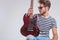 artist pose in studio looking away with guitar in hand, on knee, in studio