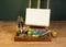 Artist studio easel palette watercolors and brushes with empty white canvas