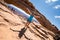 Artistic angle of a beautiful fit attractive woman standing with arms out at Mesa Arch in Canyonlands National Park