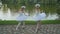 Artistic ballerinas dances near the pond in park
