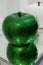 Artistic Depiction of Green Apple made of Colored and Brilliant Glass Reflecting on the Mirrored supporting Surface