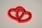 An artistic digital rendition of a neon sign featuring two interlinked hearts, glowing in a deep red hue for Valentine\'s Day