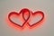 An artistic digital rendition of a neon sign featuring two interlinked hearts, glowing in a deep red hue for Valentine\'s Day