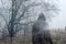 An artistic, double exposure of a hooded man on a country path on a moody foggy winters day. With a grunge, blurred edit.