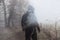 An artistic, double exposure of a hooded man on a country path on a moody foggy winters day. With a grunge, blurred edit