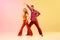Artistic, expressive man and woman in stylish clothes dancing disco, retro dance against gradient pink yellow background
