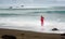 Artistic fine art picture about a red, long dressed beautiful blonde woman, who stands on a beach rock in the water.