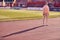 Artistic image of young adult woman standing on athlete track at stadium, posing, with sharp and long shadow. big copy space