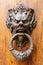 Artistic large face as a door knocker on an antique door in Italy