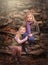 Artistic outdoor portrait of two blond girls sitting on rocks