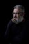 Artistic portrait of a brutal gray haired man with a beard and glasses on a black background, selective focus