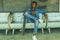 Artistic portrait of young attractive and fit black African American man sitting on corner street bench holding skate board posing