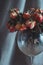 Artistic shot of faded coral pink roses in a dust covered wine glass