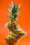 Artistic sliced, standing pineapple on orange background, vertical shot