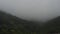 An artistic timelapse view capturing first ? downpour, and then fog the background of green mountains. Heavy rain, fog.