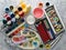 Artistic tools for drawing paintings on a gray concrete background. Palette, gouache, oil paint, brushes, colored crayons, pastel