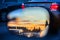 An artistic view of the busy traffic via side mirror at sunset in Los Angeles. Blurred road, headlights and rear lights