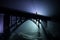 Artwork decoration. Silhouette of powerful metallic bridge at night with foggy backlight. Silhouette of person standing on bridge