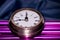 Arty shot of a metal large pocket watch clock on purple pipes