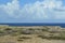 Aruba desert meets ocean with billowing clouds in blue sky