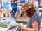 ARUTANGA, AITUTAKI, COOK ISLAND - SEPTEMBER 30, 2018: Woman in a wreath of flowers reading a newspaper on a city street.