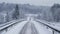 As frigid winds howl through the frozen landscape a narrow snowcovered road ss its way through the foreground flanked by