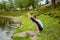 A asana sports girl practices yoga on a green lawn by the river, yoga assans posture. Meditation and unity with nature.