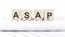 ASAP -word wooden block on keyboard background witn chart