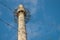 Asbestos-cement boiler house pipe installed vertically, supported by system of metal tripwires, with observation platform at top