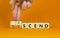 Ascend or descend symbol. Concept words Ascend and Descend on wooden cubes. Beautiful orange table orange background. Businessman