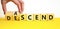 Ascend or descend symbol. Concept words Ascend and Descend on wooden cubes. Beautiful yellow table white background. Businessman