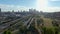 ascending aerial footage of people in the park with skyscrapers in the city skyline, lush green trees and grass with cars driving