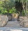 Ascending marble stairs leading to a public park, Stone wall, and fence iron door