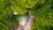 ascending shot of a small waterfall and lake in the green forest, aerial