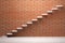 Ascending stairs in empty room with red brick wall