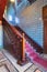 Ascending wooden staircase with ornate red carpet, decorated wooden balustrade and Turkish ceramic tiles wall